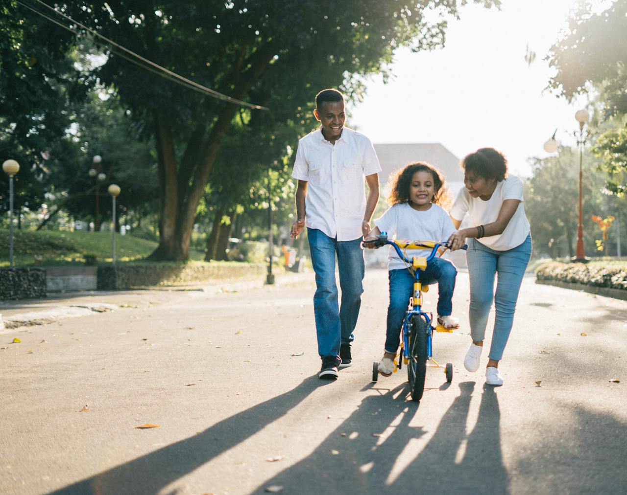 services-02 Happy family teaching their child to cycle on a sunny day outdoors.