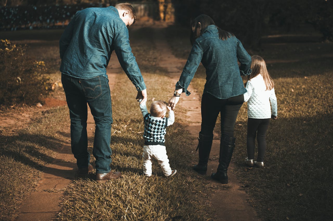 hero-img-02 A family of four walks hand in hand on a path, enjoying a sunny day outdoors.
