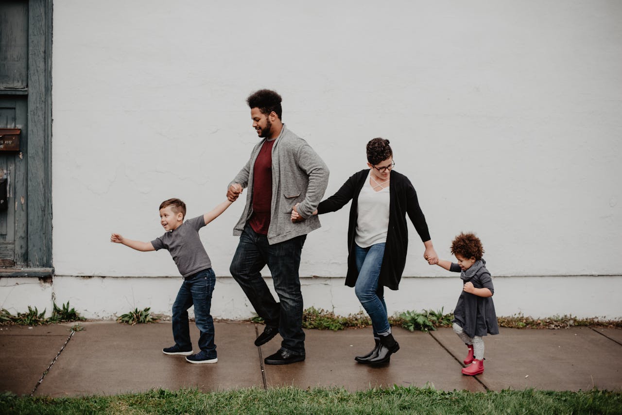 hero-img-01 A joyful family walking together outdoors, holding hands in a playful and happy moment.