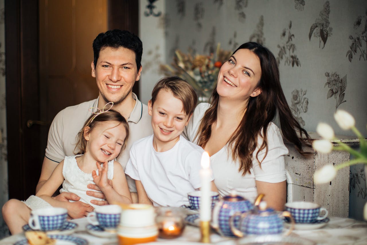 services-01 Cheerful family of four enjoying a warm and cozy teatime at home, surrounded by love and laughter.